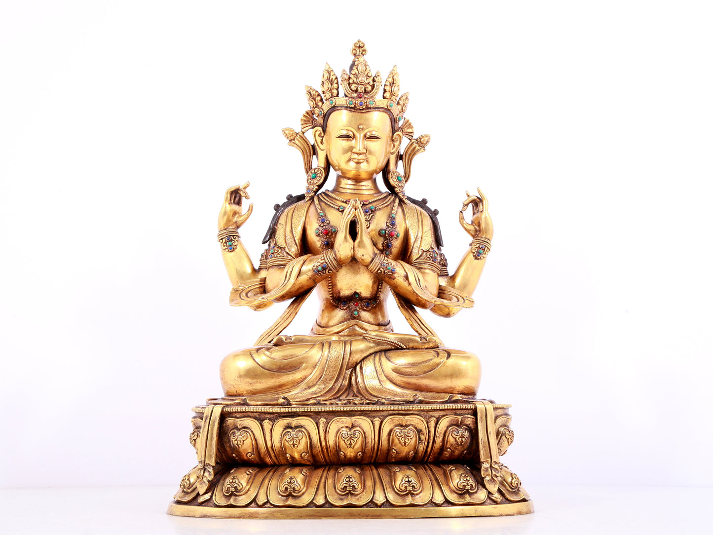 A solemn gilt bronze statue of Guanyin with four arms inlaid gems