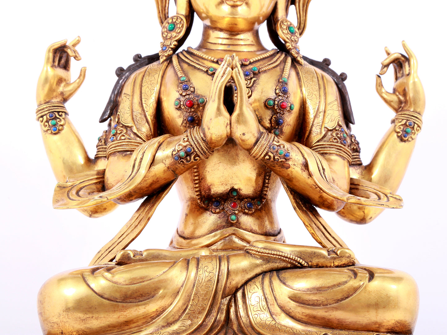 A solemn gilt bronze statue of Guanyin with four arms inlaid gems