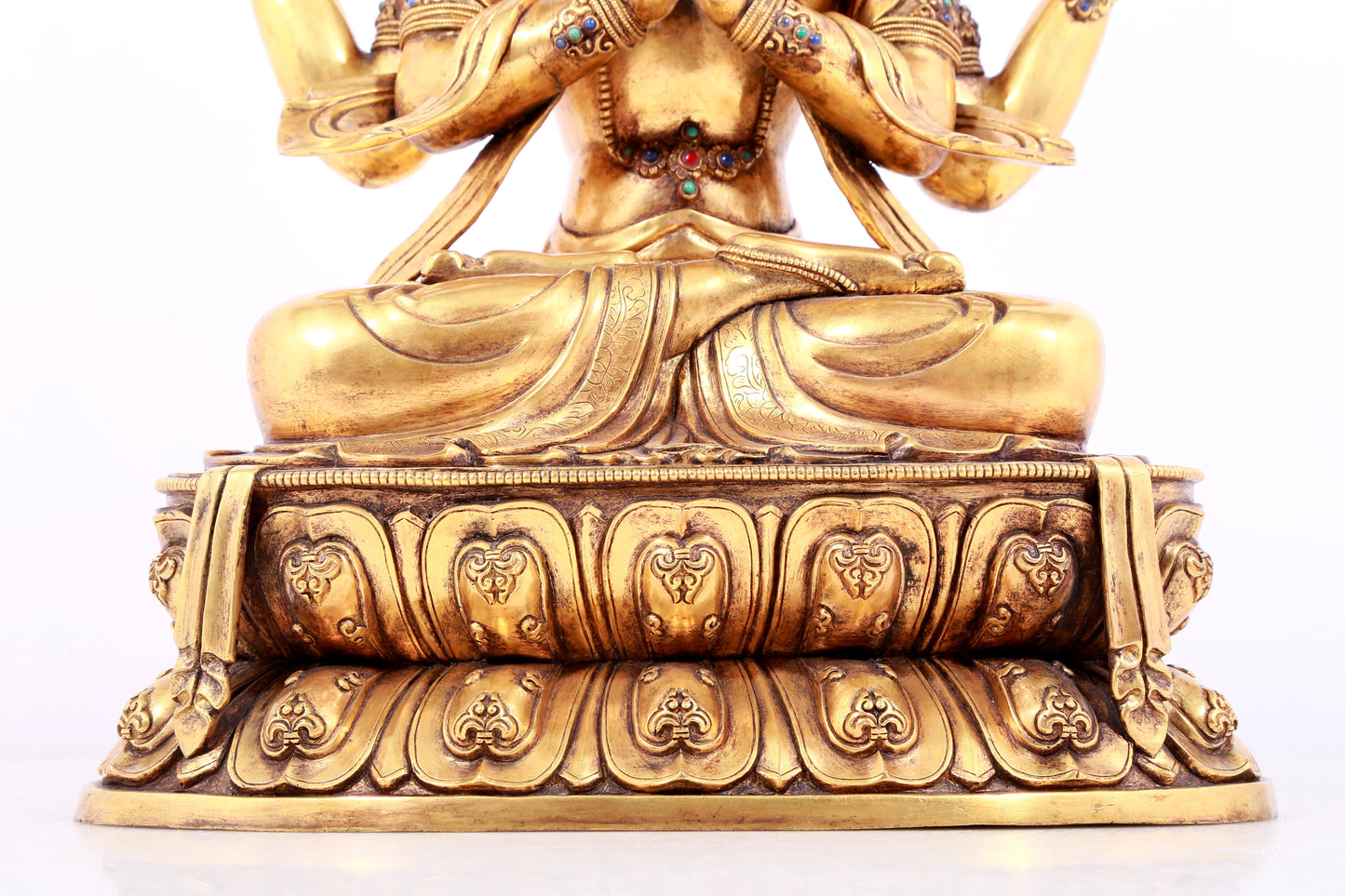 A solemn gilt bronze statue of Guanyin with four arms inlaid gems