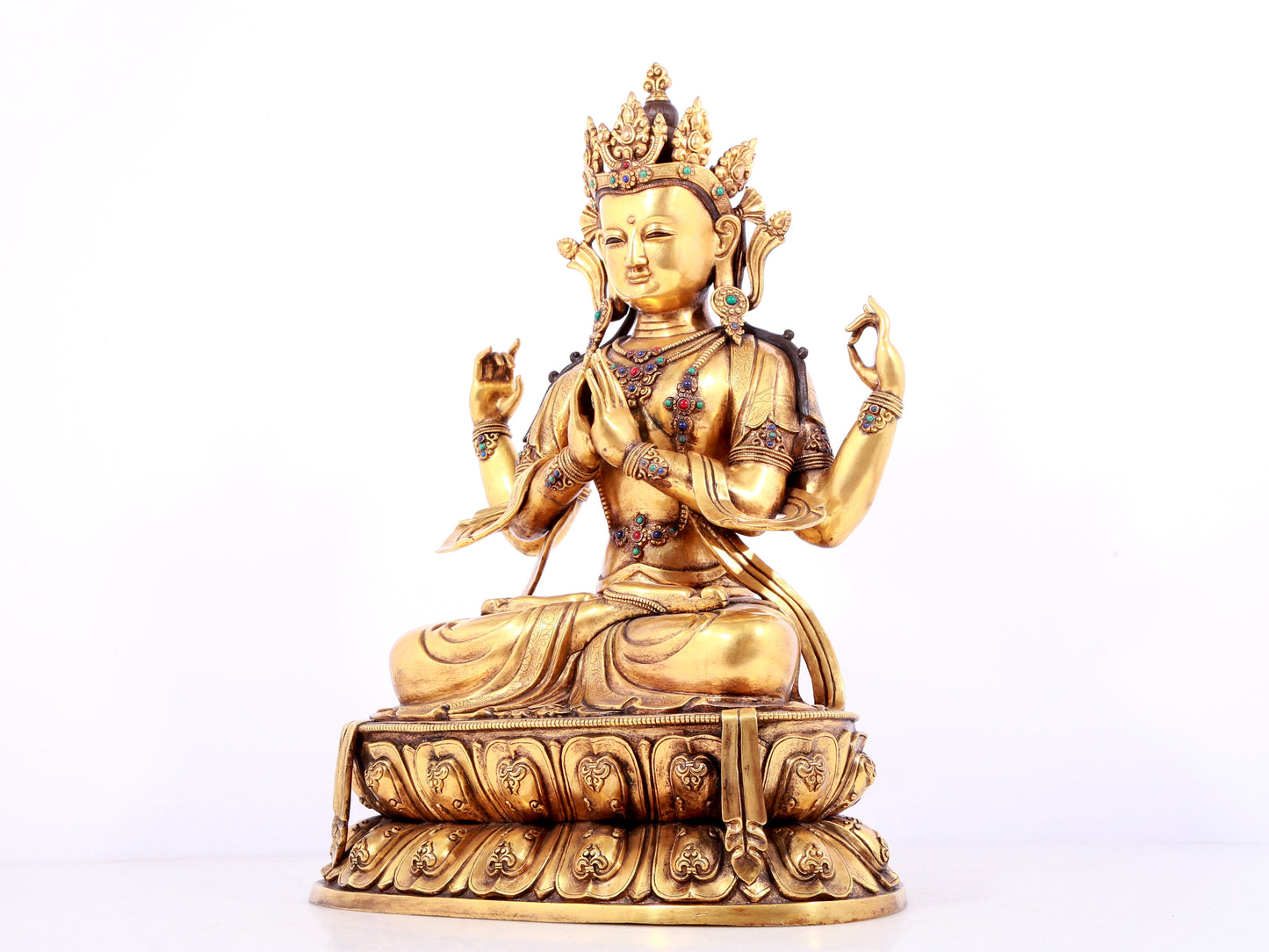 A solemn gilt bronze statue of Guanyin with four arms inlaid gems