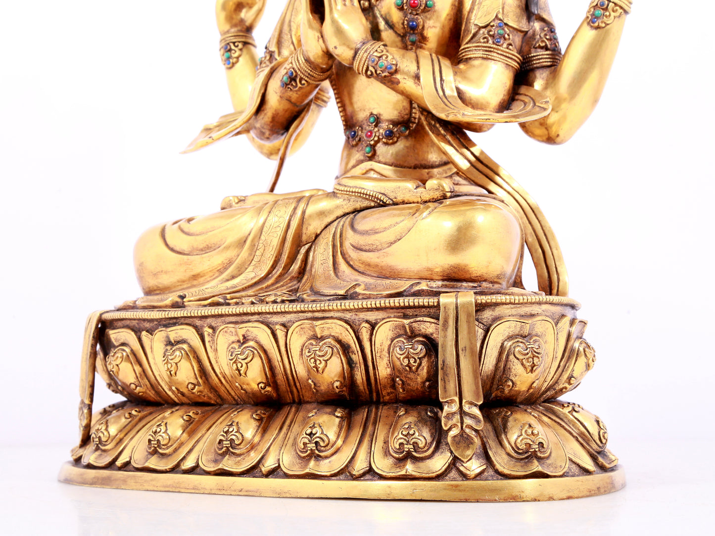 A solemn gilt bronze statue of Guanyin with four arms inlaid gems