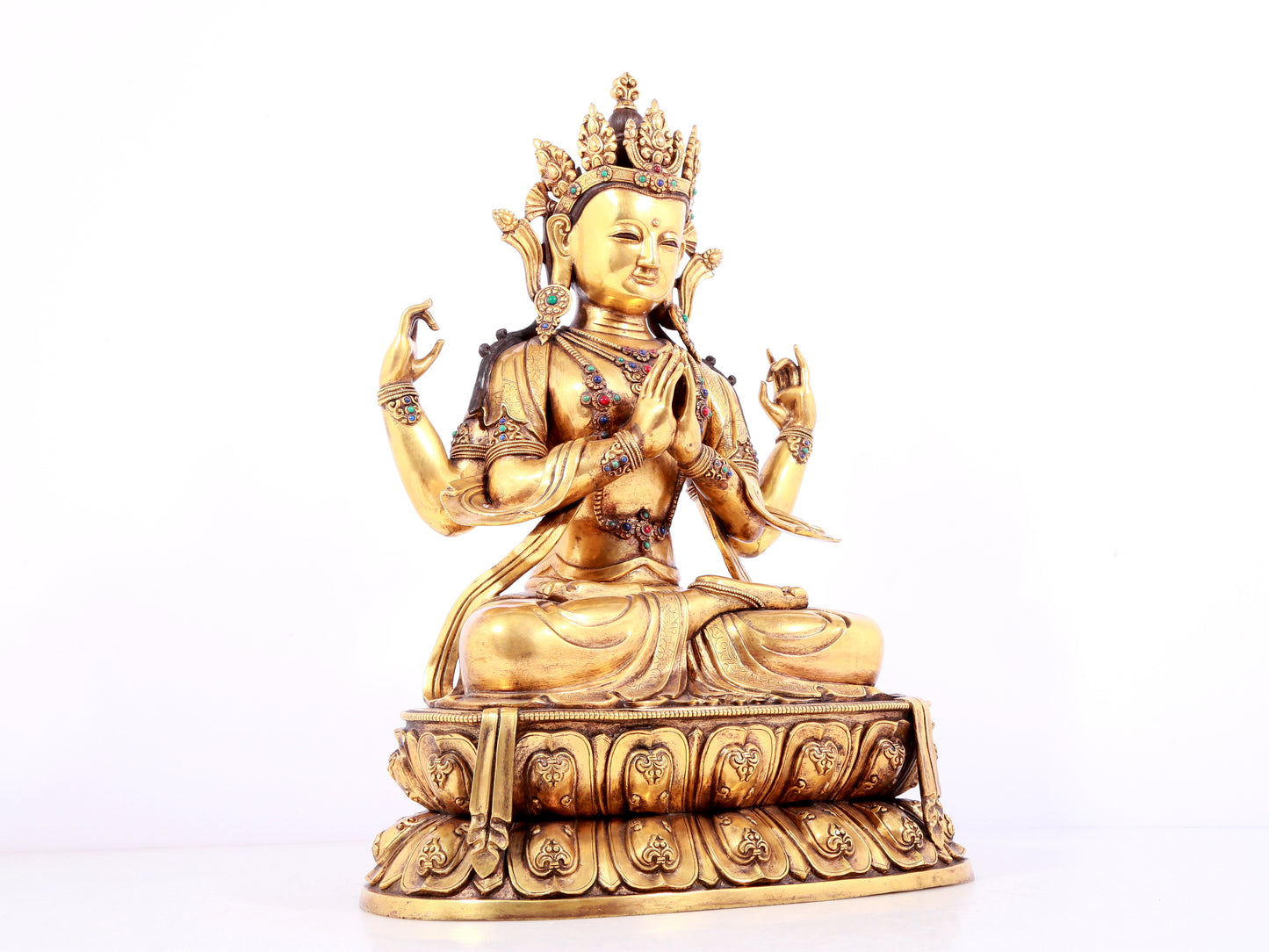 A solemn gilt bronze statue of Guanyin with four arms inlaid gems