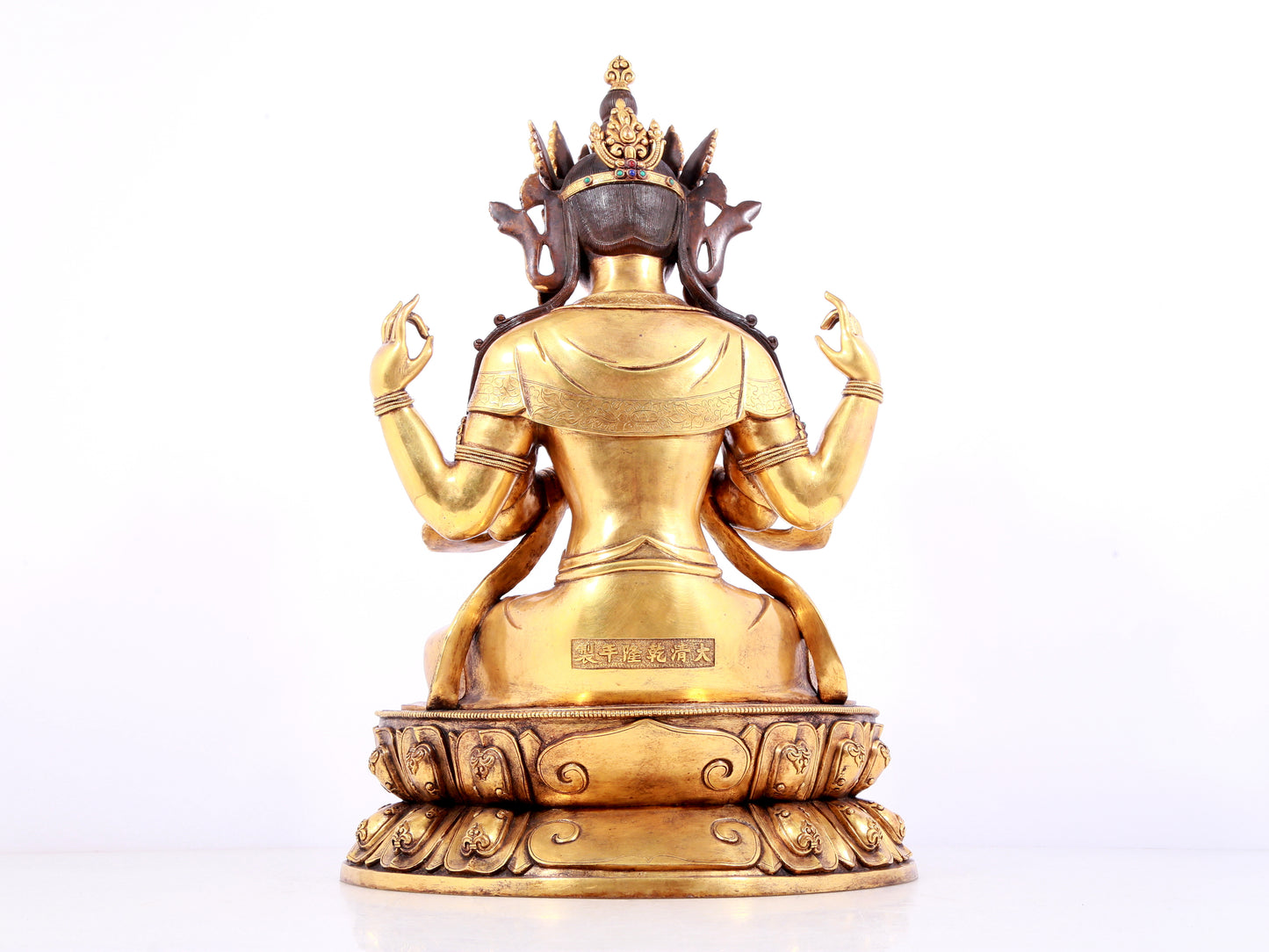 A solemn gilt bronze statue of Guanyin with four arms inlaid gems