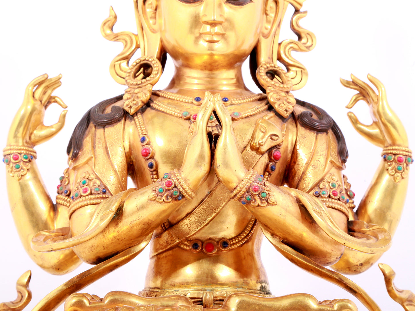 A solemn gilt bronze statue of Guanyin with four arms inlaid gems