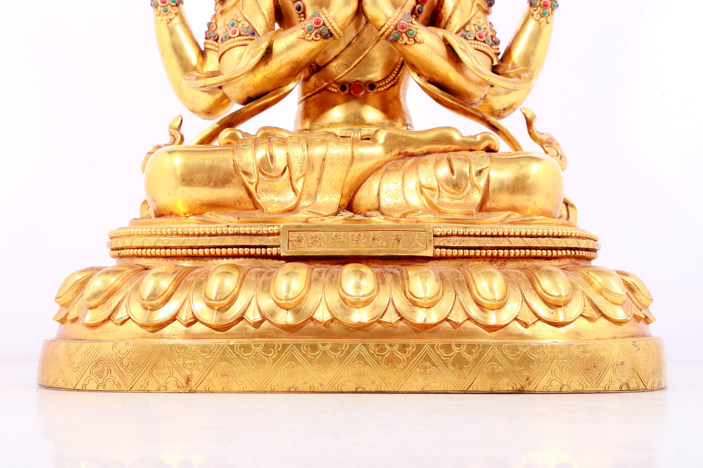 A solemn gilt bronze statue of Guanyin with four arms inlaid gems