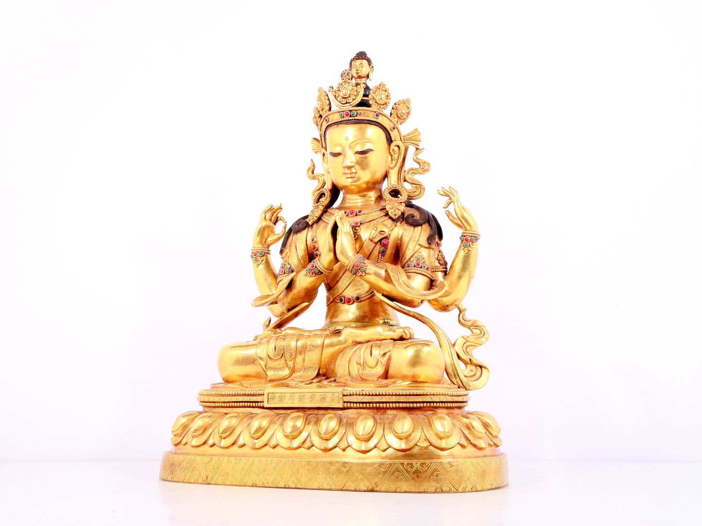 A solemn gilt bronze statue of Guanyin with four arms inlaid gems