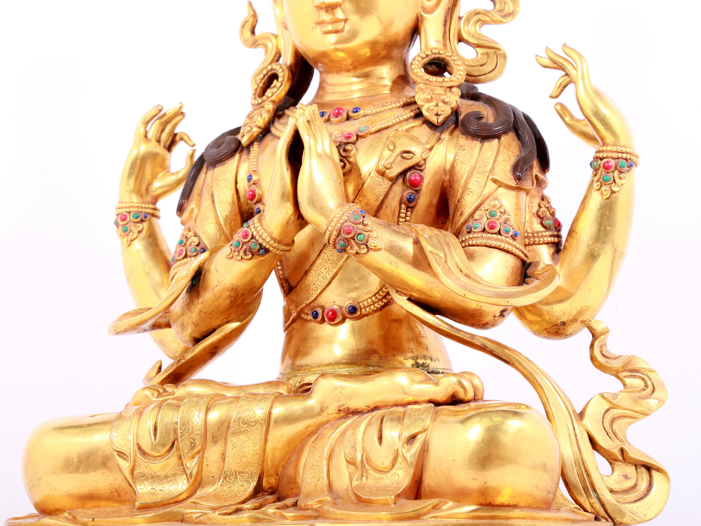 A solemn gilt bronze statue of Guanyin with four arms inlaid gems