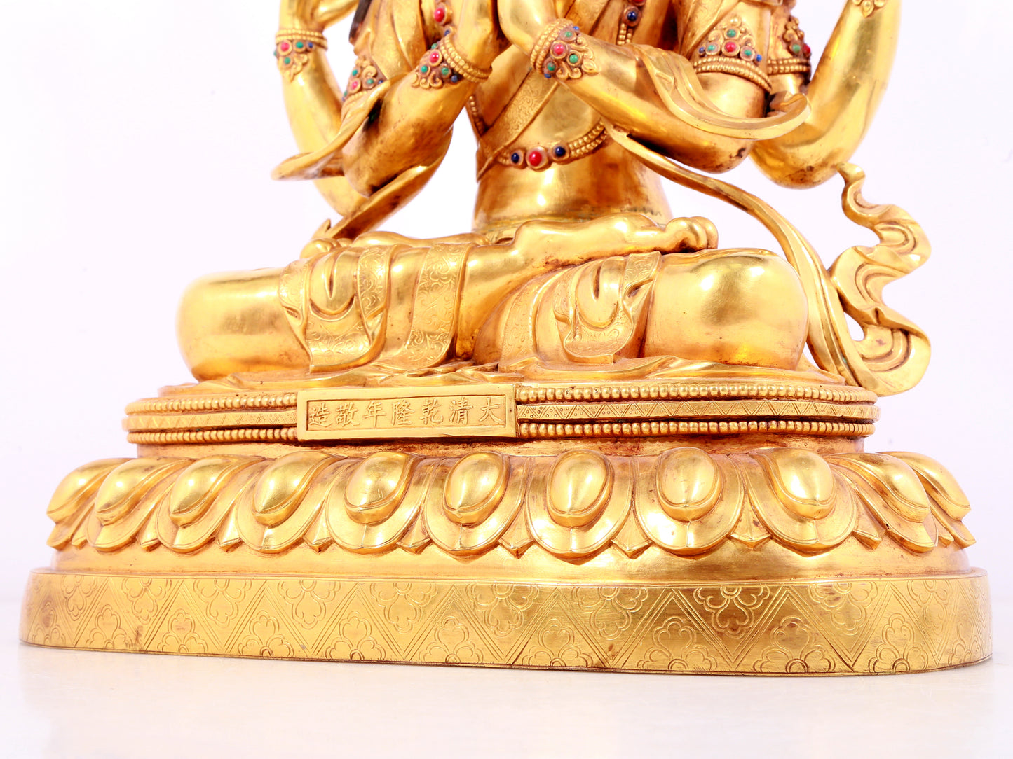 A solemn gilt bronze statue of Guanyin with four arms inlaid gems