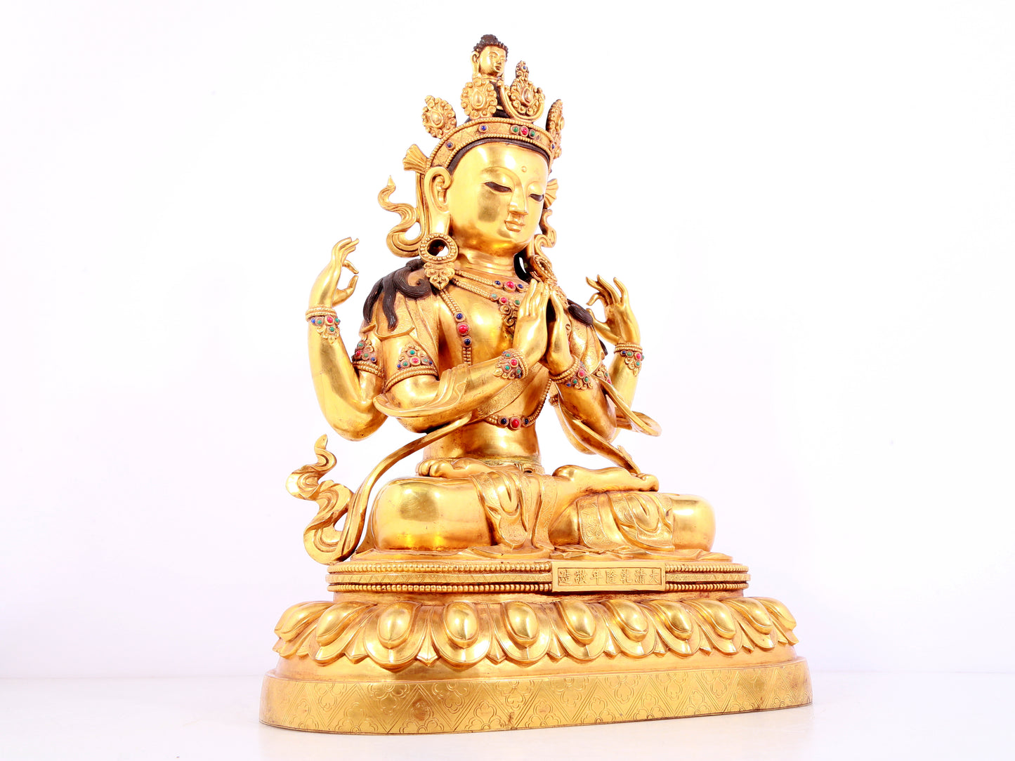 A solemn gilt bronze statue of Guanyin with four arms inlaid gems