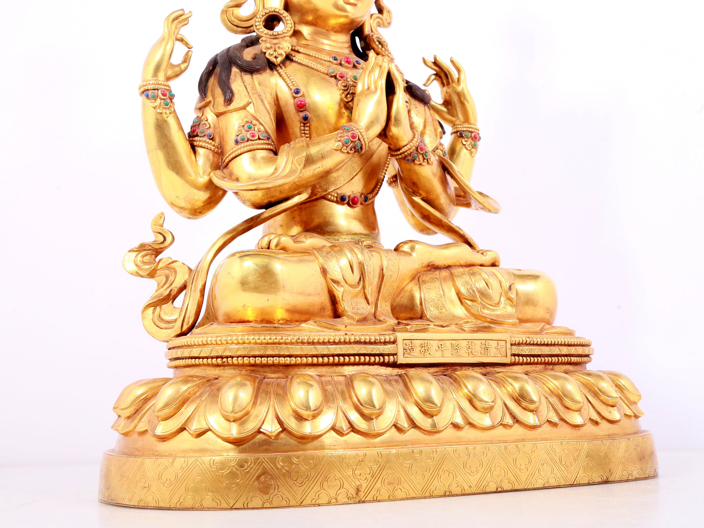 A solemn gilt bronze statue of Guanyin with four arms inlaid gems