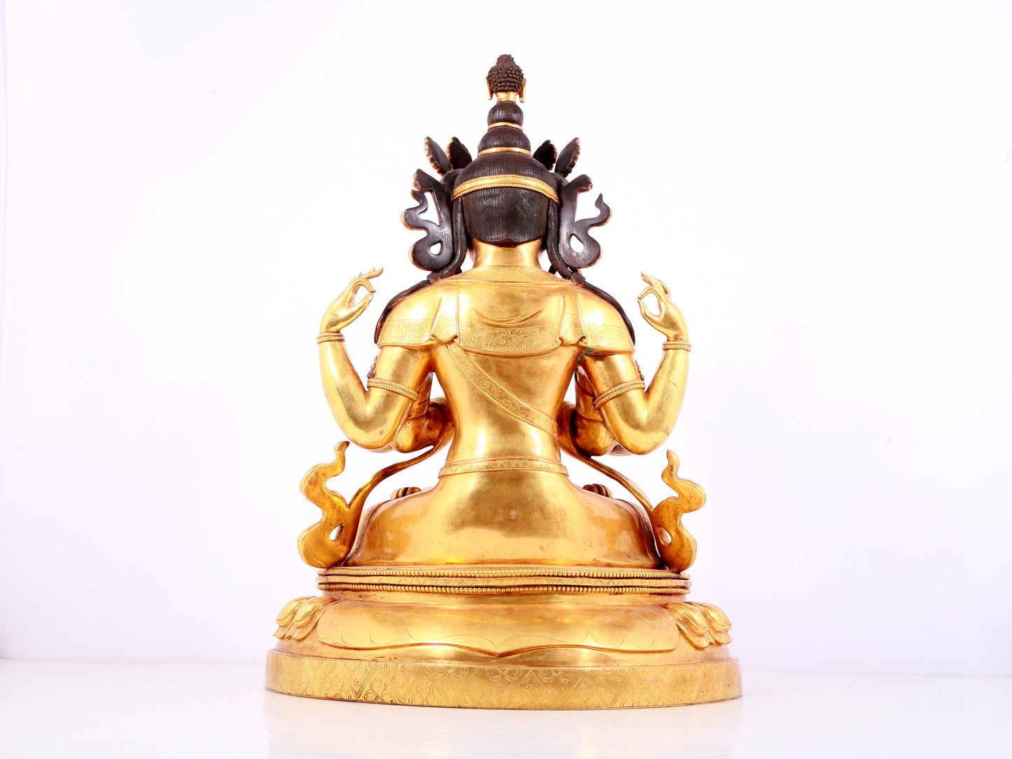 A solemn gilt bronze statue of Guanyin with four arms inlaid gems