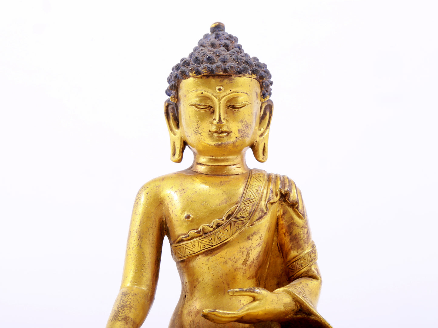 A serene gilt bronze statue of Gautama Buddha