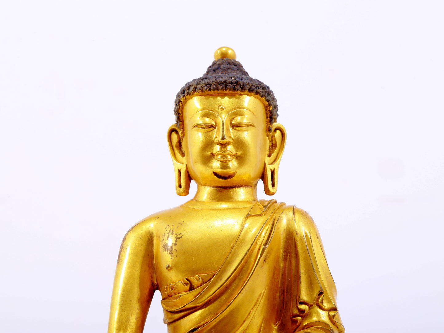 A serene gilt bronze statue of Gautama Buddha