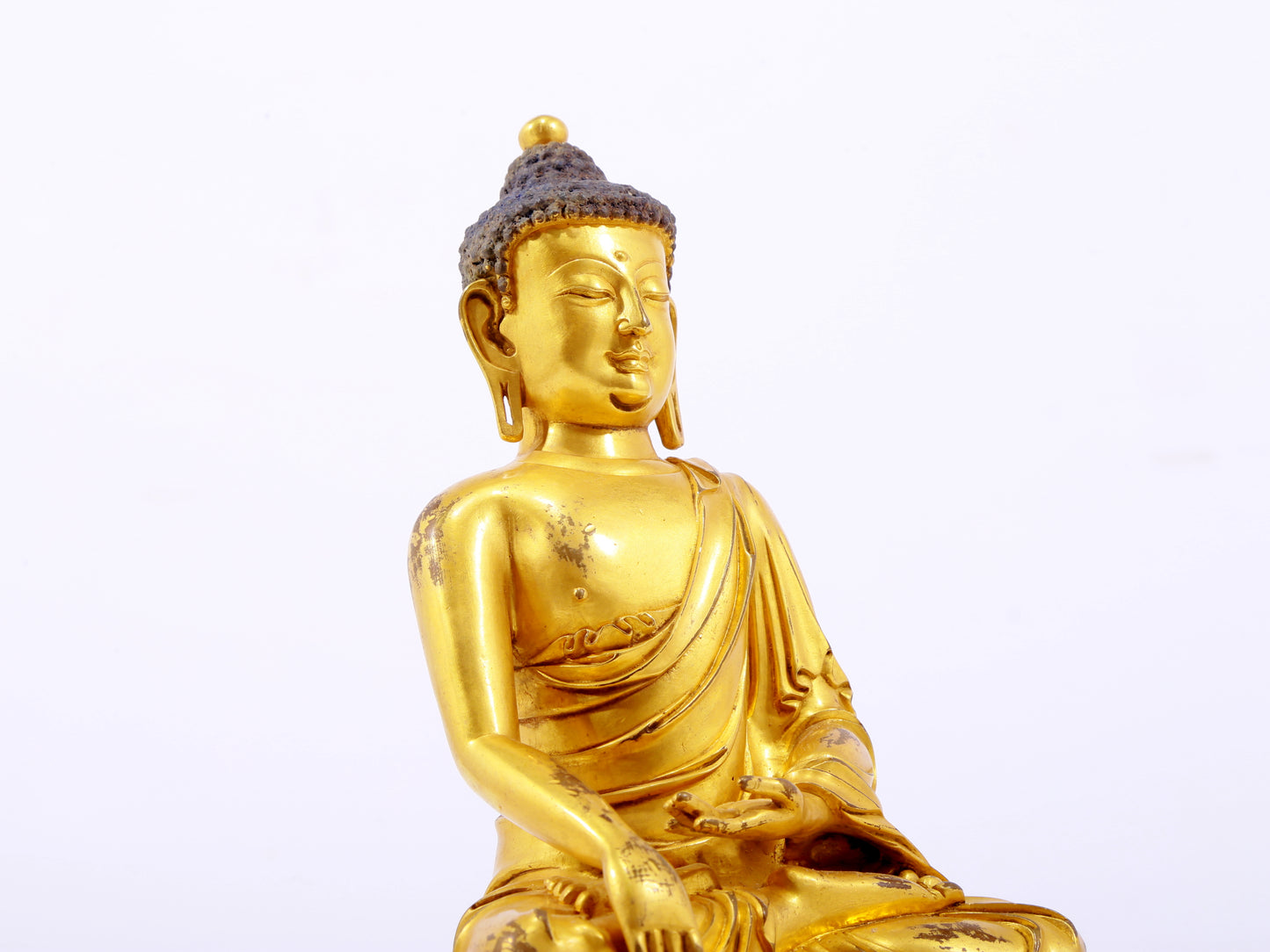 A serene gilt bronze statue of Gautama Buddha