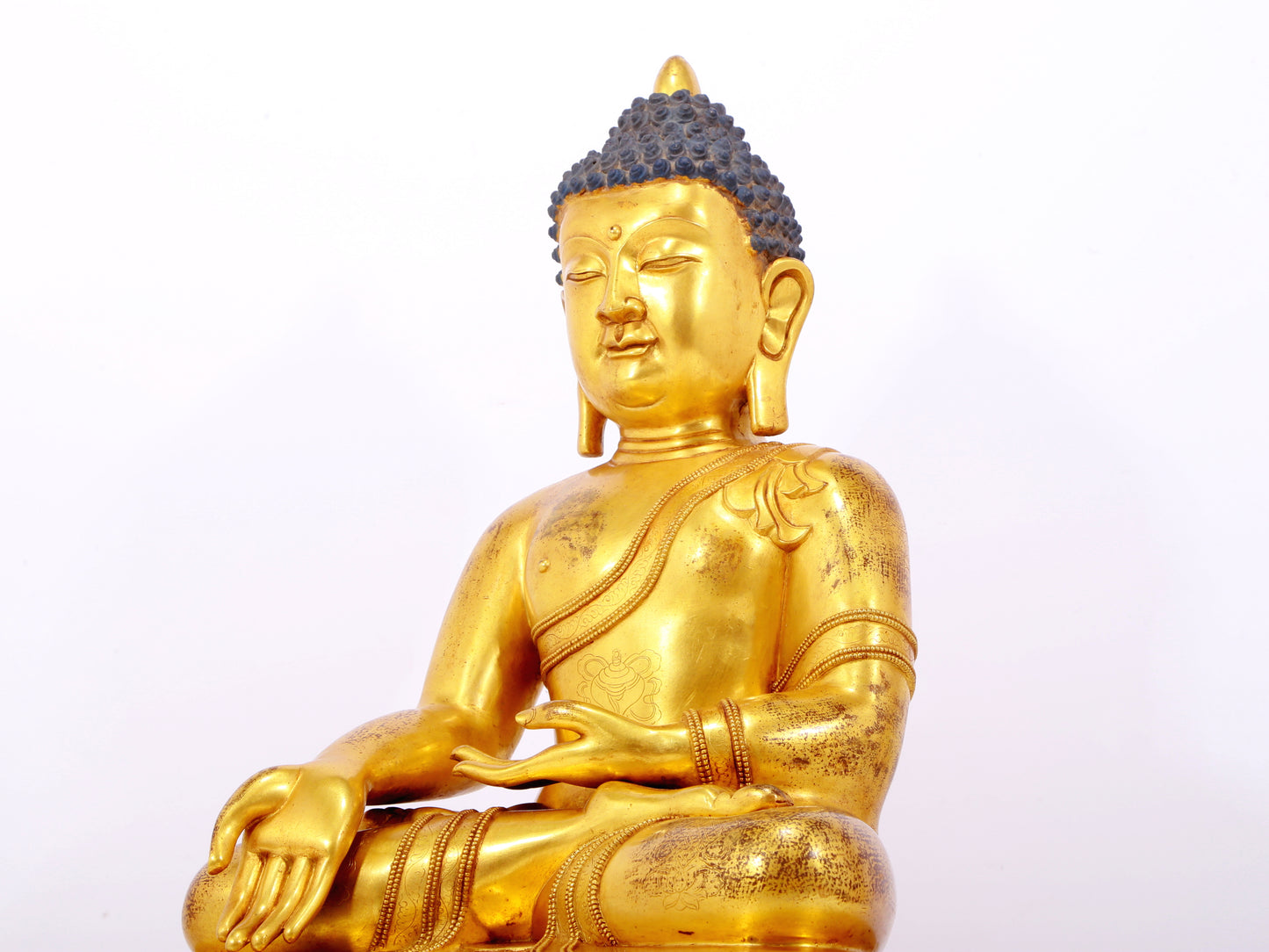 A serene gilt bronze statue of Gautama Buddha