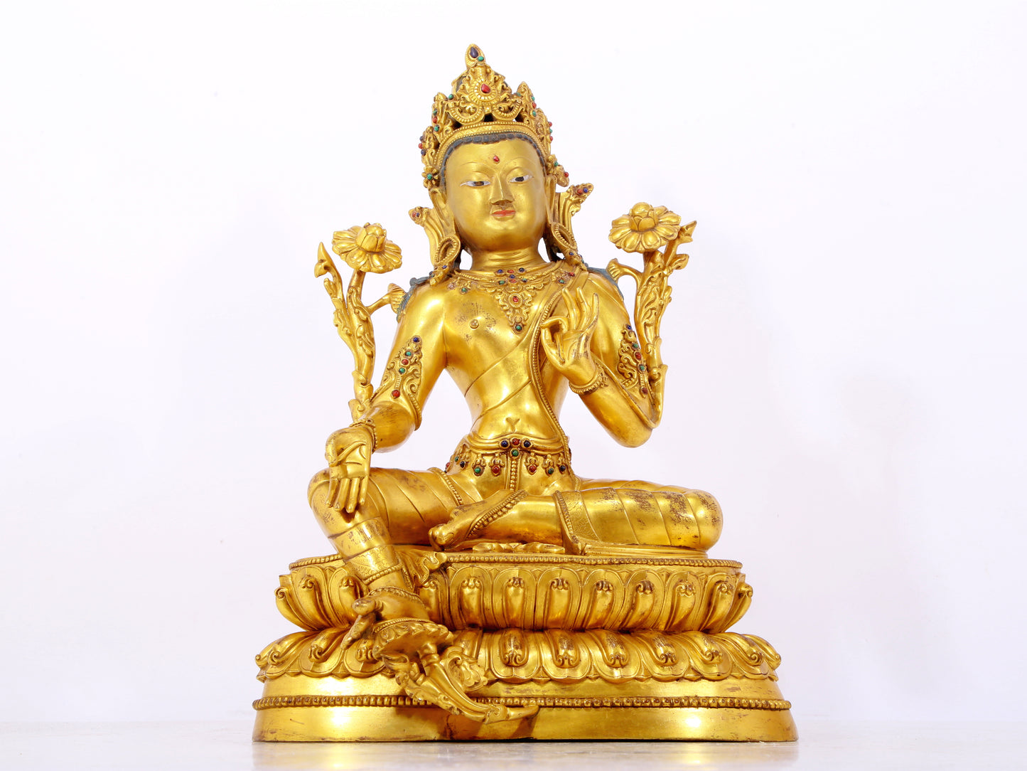 A serene gilt bronze statue of Tara inlaid with sapphire green