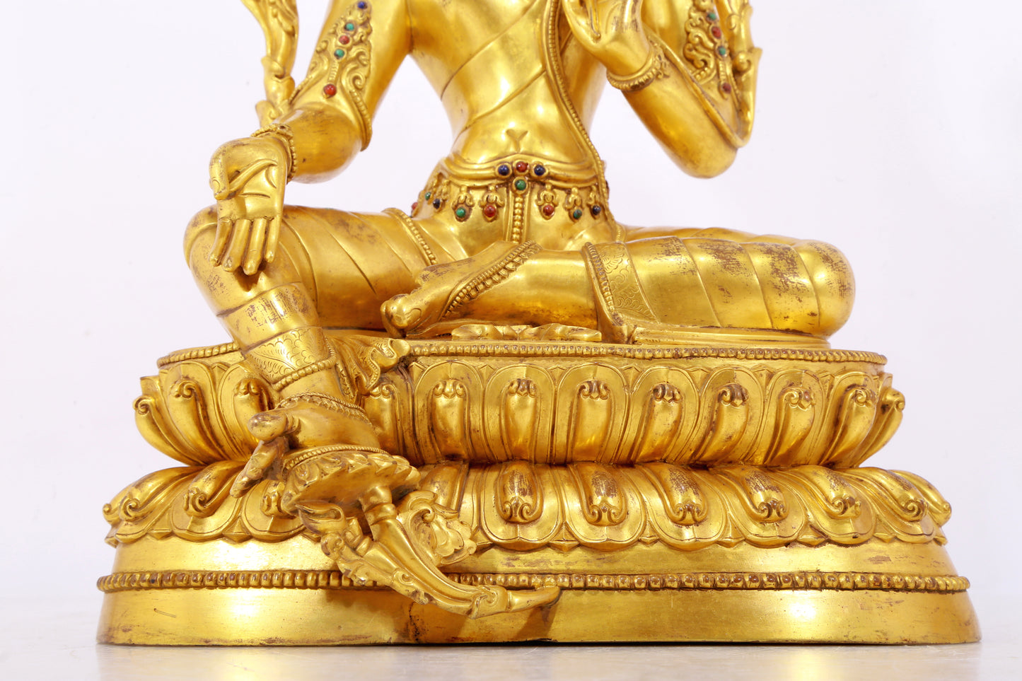 A serene gilt bronze statue of Tara inlaid with sapphire green