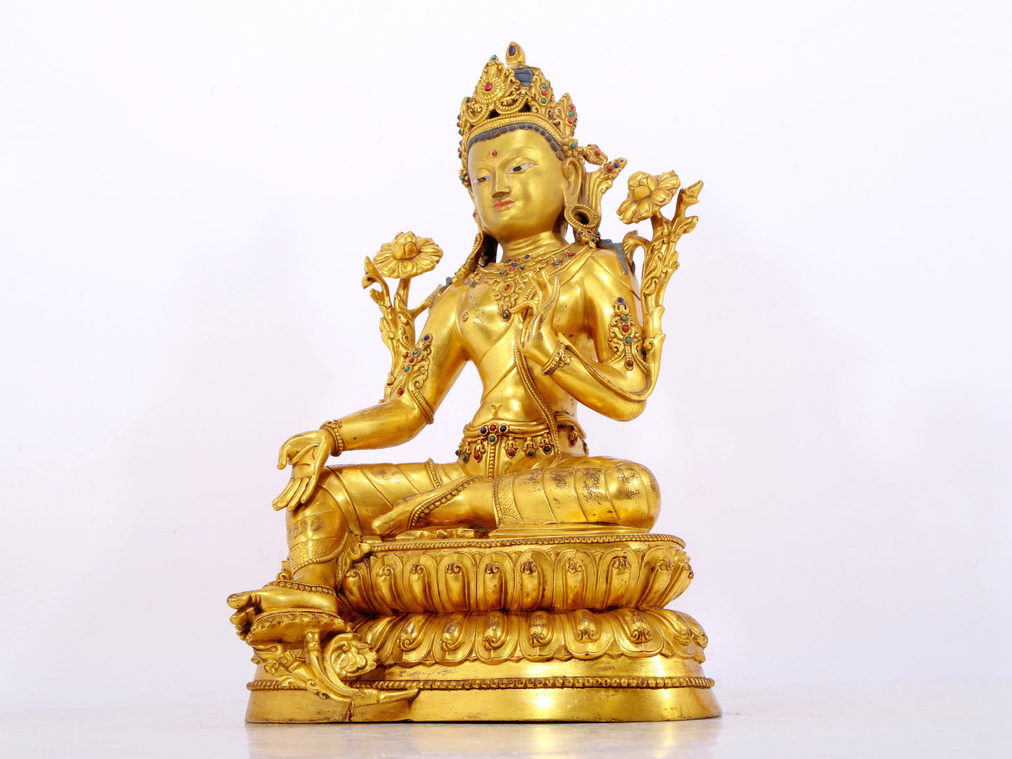 A serene gilt bronze statue of Tara inlaid with sapphire green