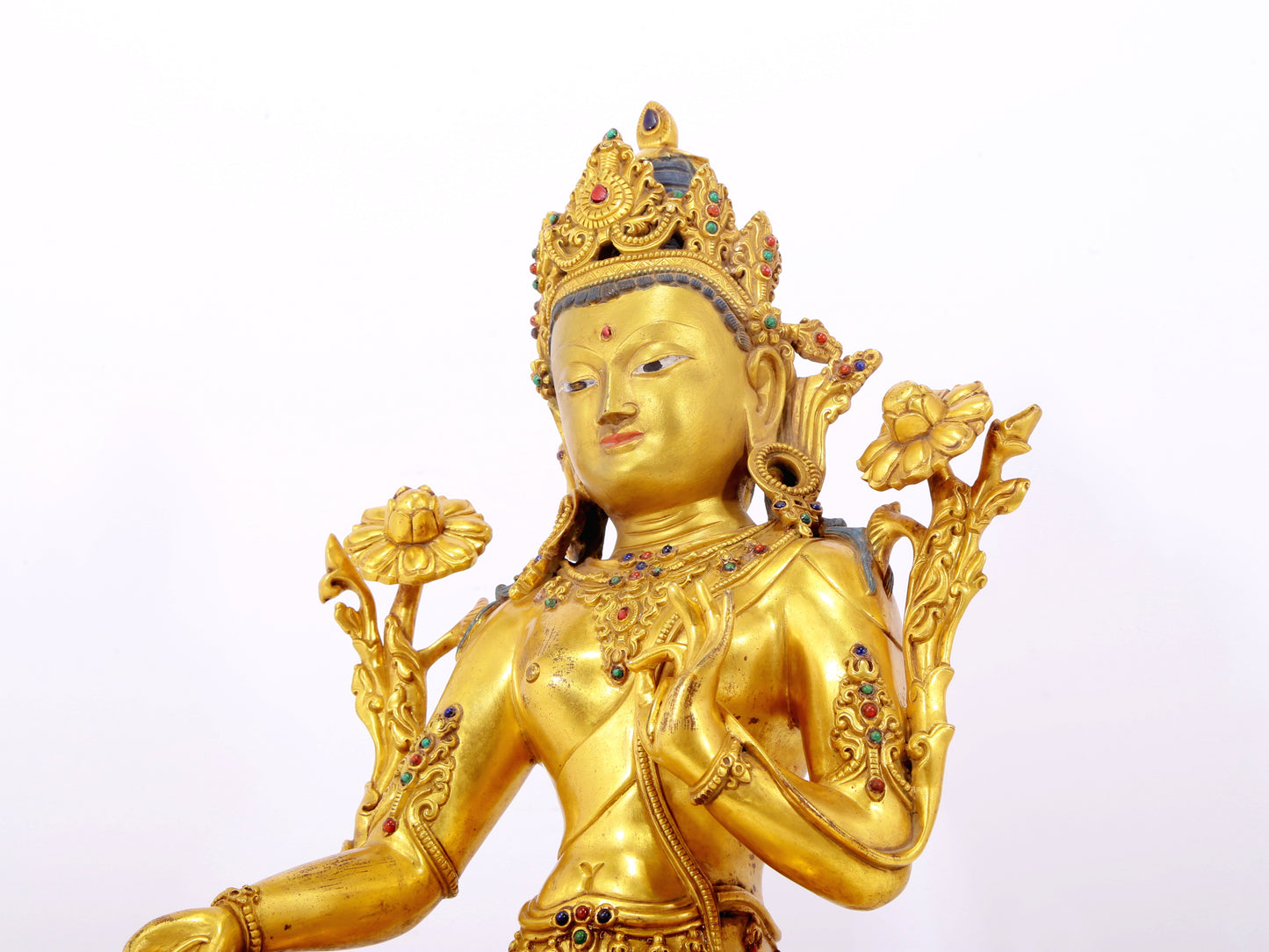 A serene gilt bronze statue of Tara inlaid with sapphire green