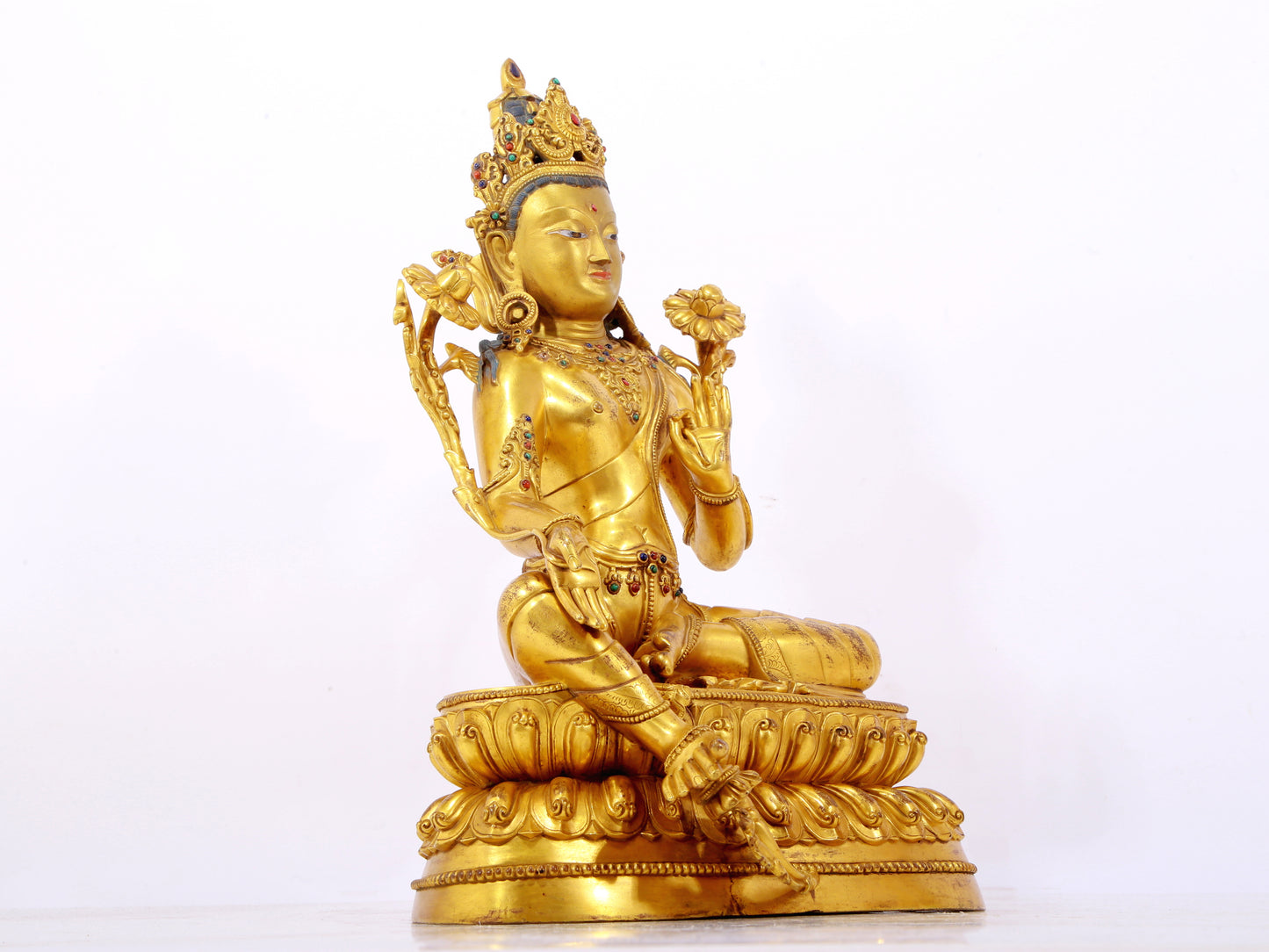 A serene gilt bronze statue of Tara inlaid with sapphire green