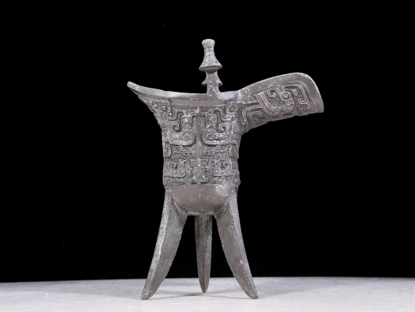 A precious bronze tripod cup with animal masks