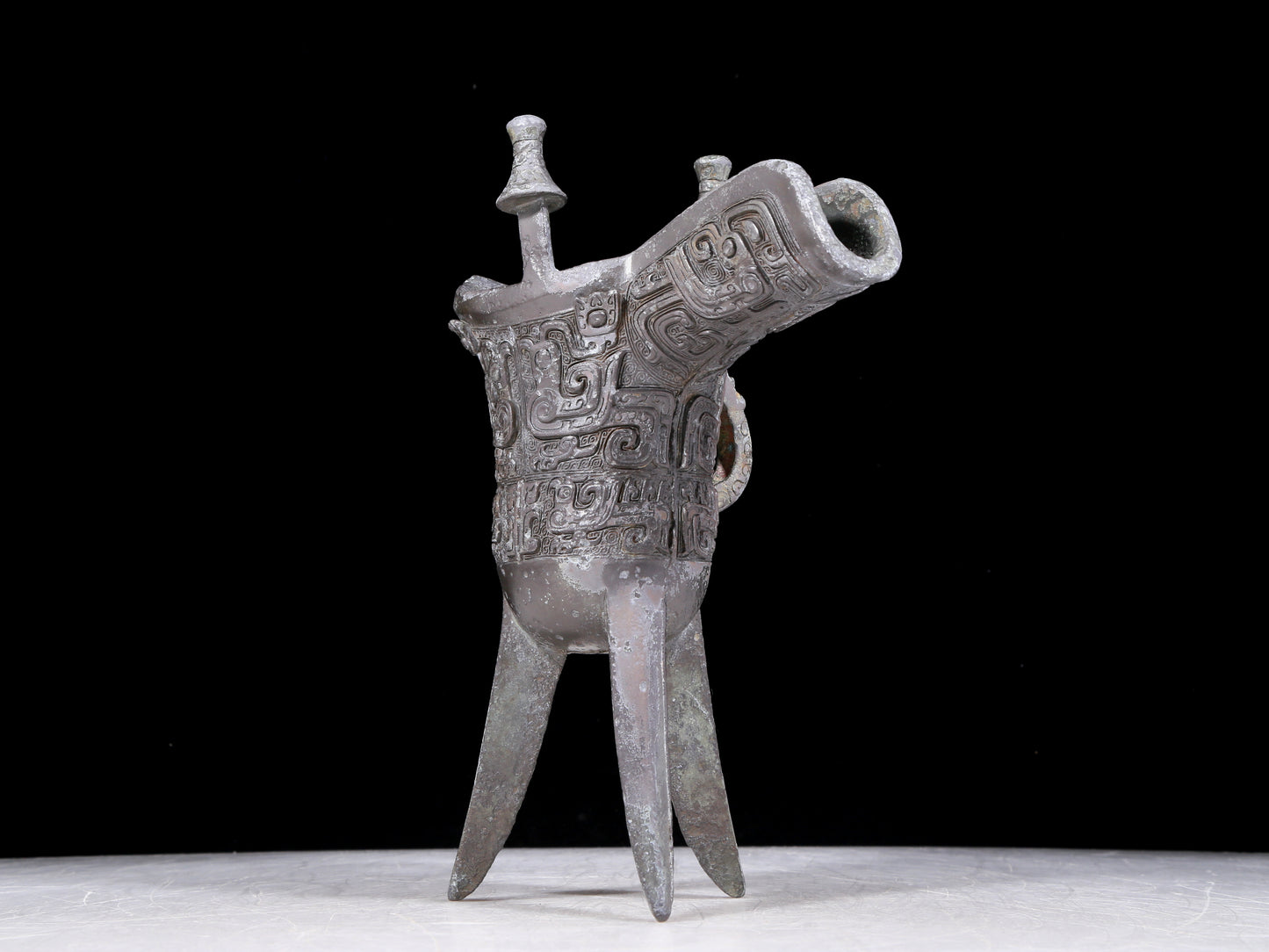 A precious bronze tripod cup with animal masks