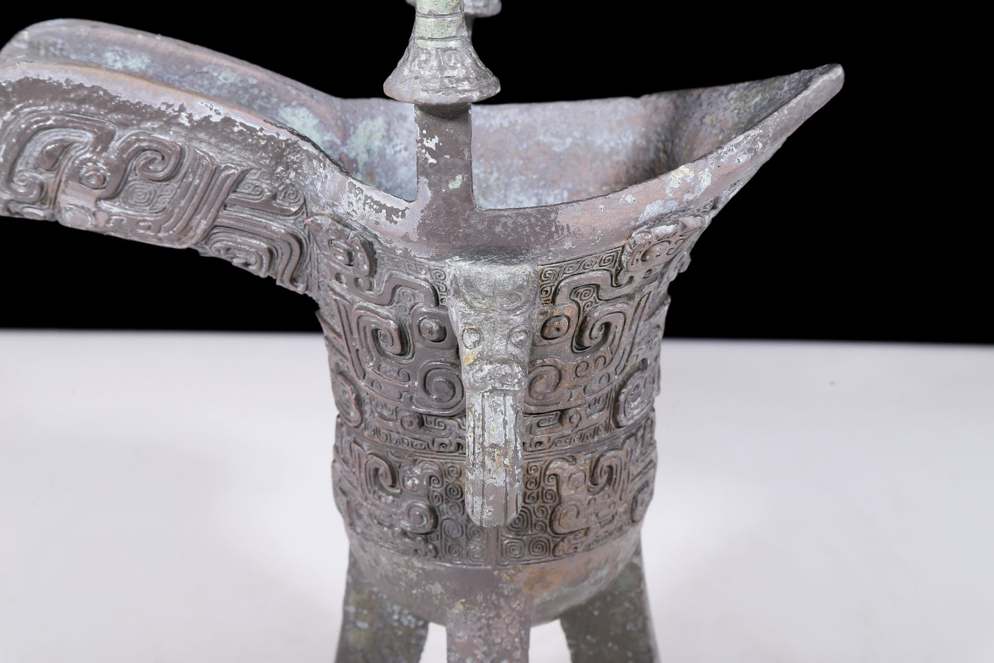 A precious bronze tripod cup with animal masks