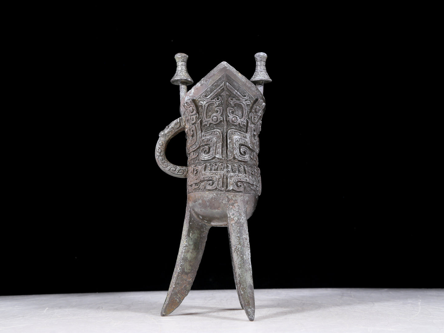 A precious bronze tripod cup with animal masks