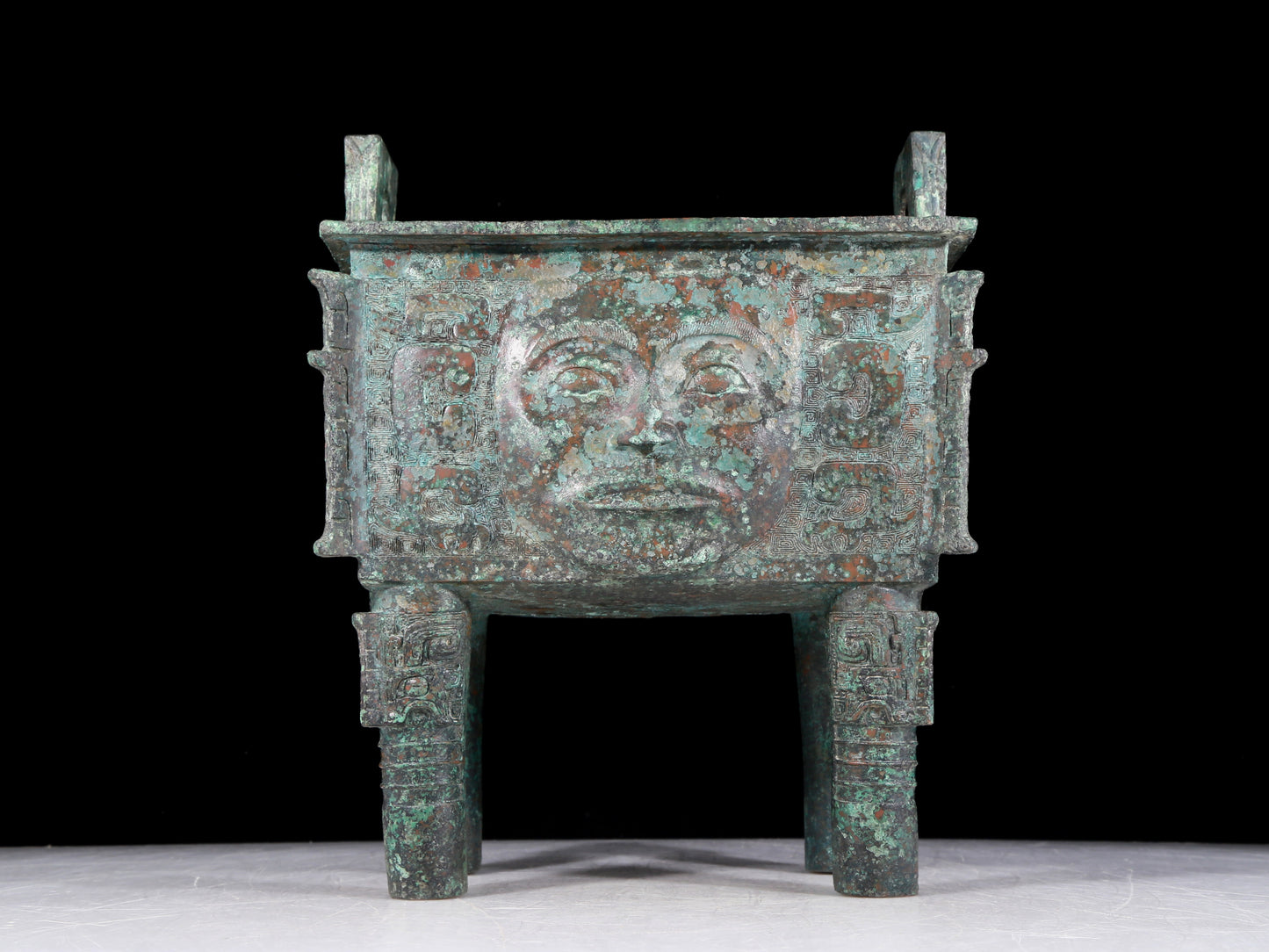 A precious bronze tripod with a human face, two ears and four legs