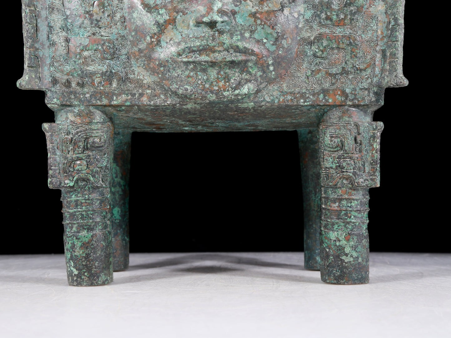 A precious bronze tripod with a human face, two ears and four legs