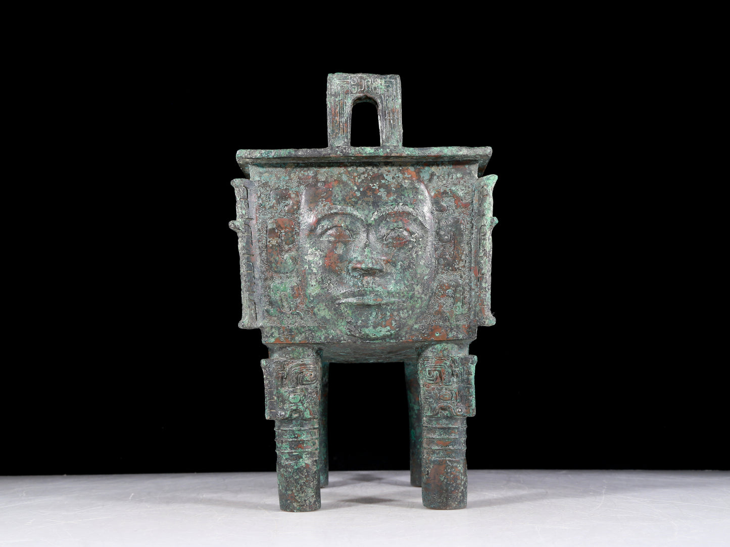 A precious bronze tripod with a human face, two ears and four legs