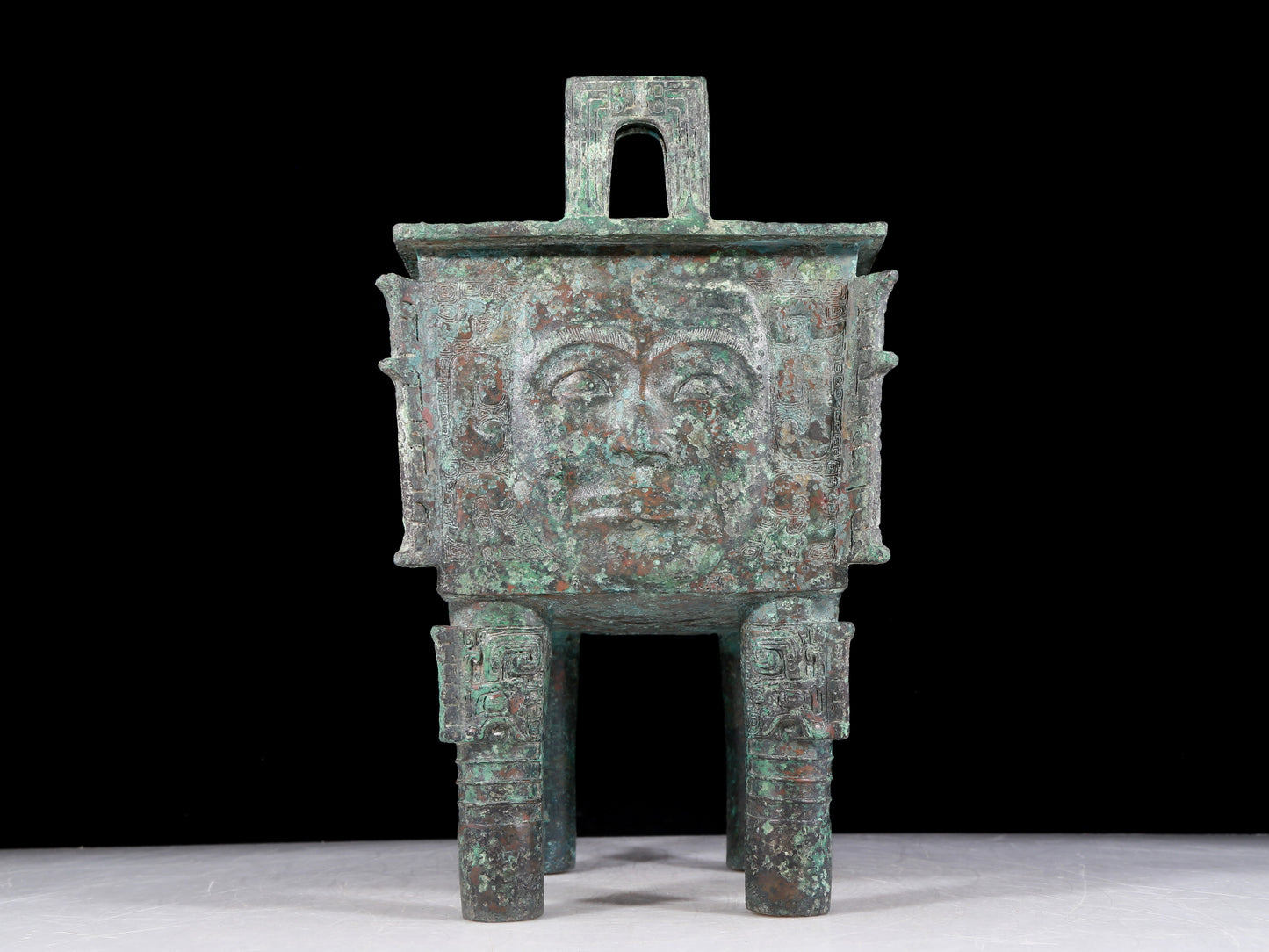 A precious bronze tripod with a human face, two ears and four legs