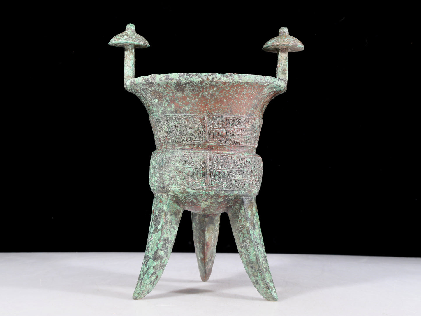 A precious bronze tripod cup with animal masks