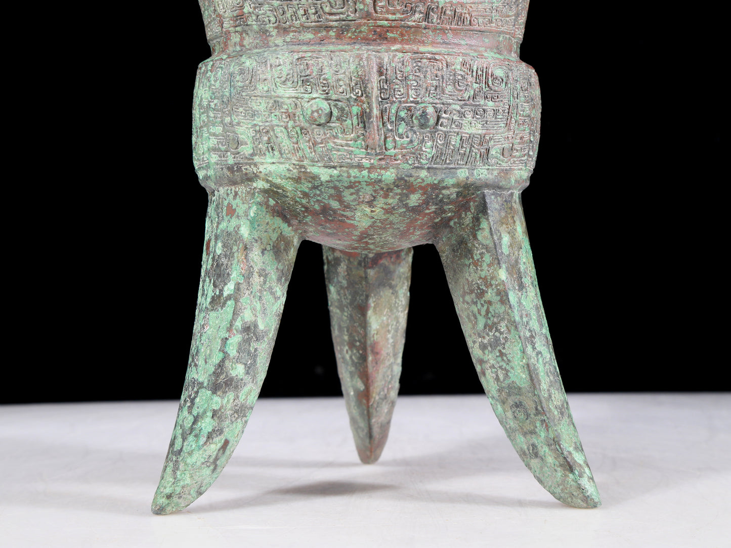 A precious bronze tripod cup with animal masks