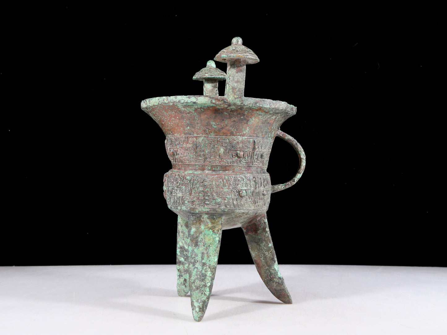 A precious bronze tripod cup with animal masks