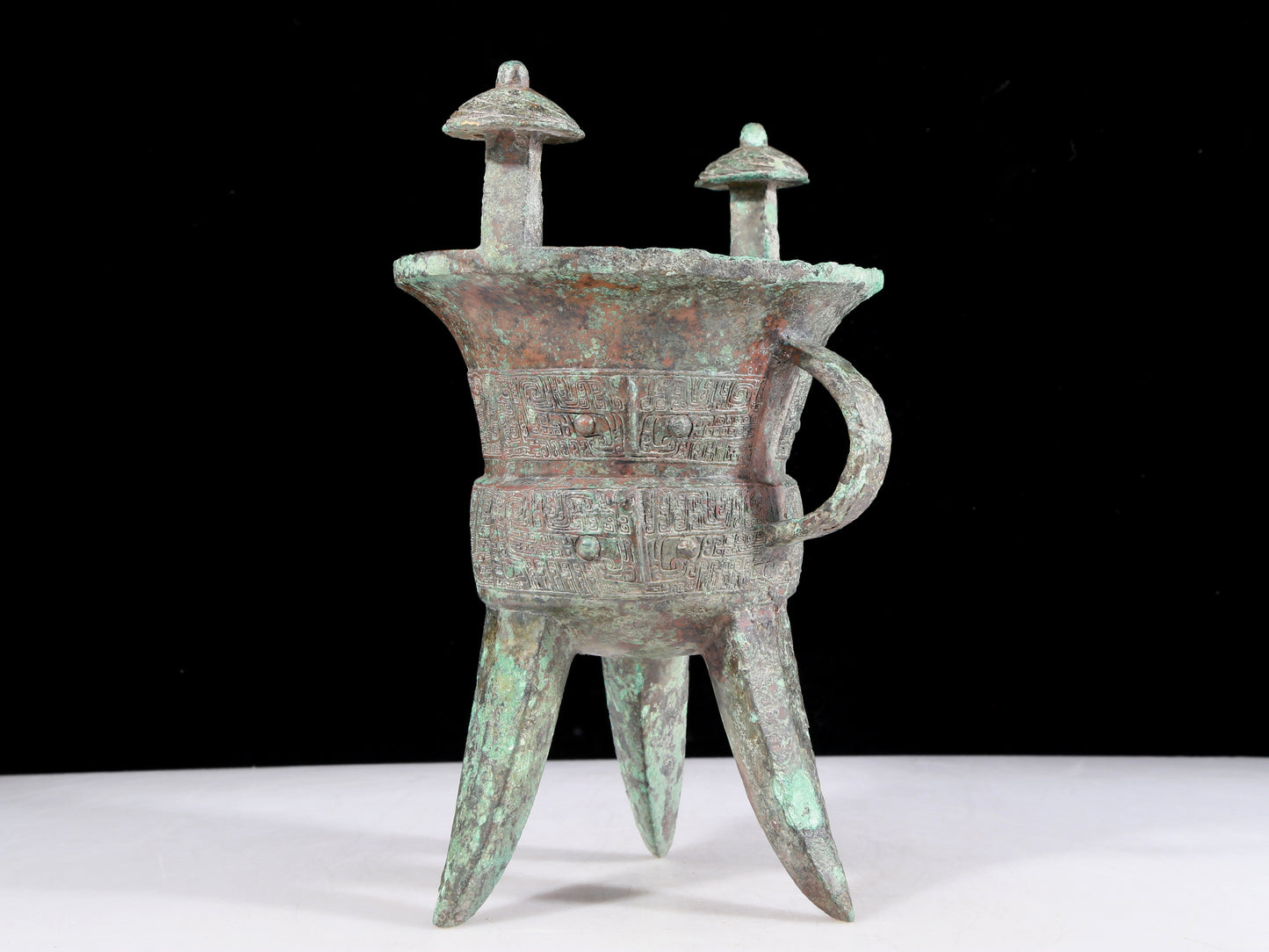 A precious bronze tripod cup with animal masks