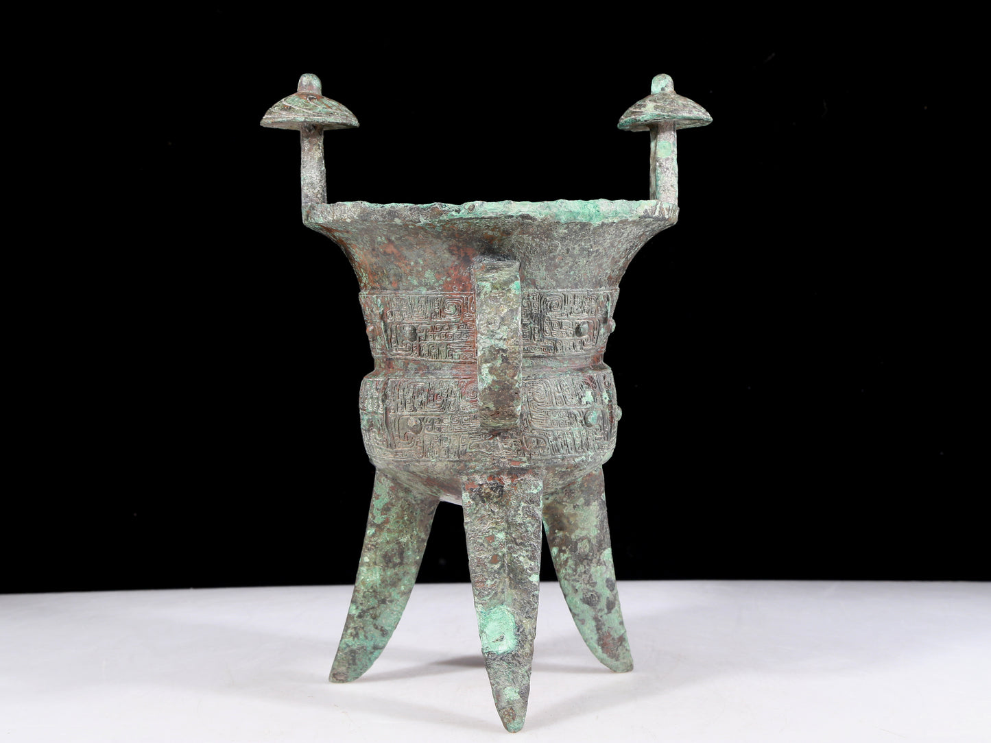 A precious bronze tripod cup with animal masks