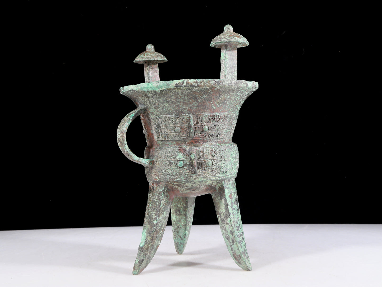 A precious bronze tripod cup with animal masks