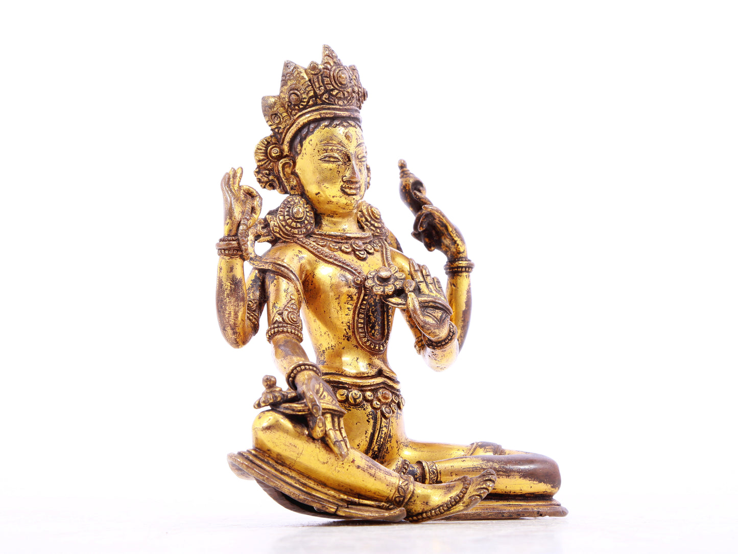 A solemn gilt bronze four-armed Guanyin statue