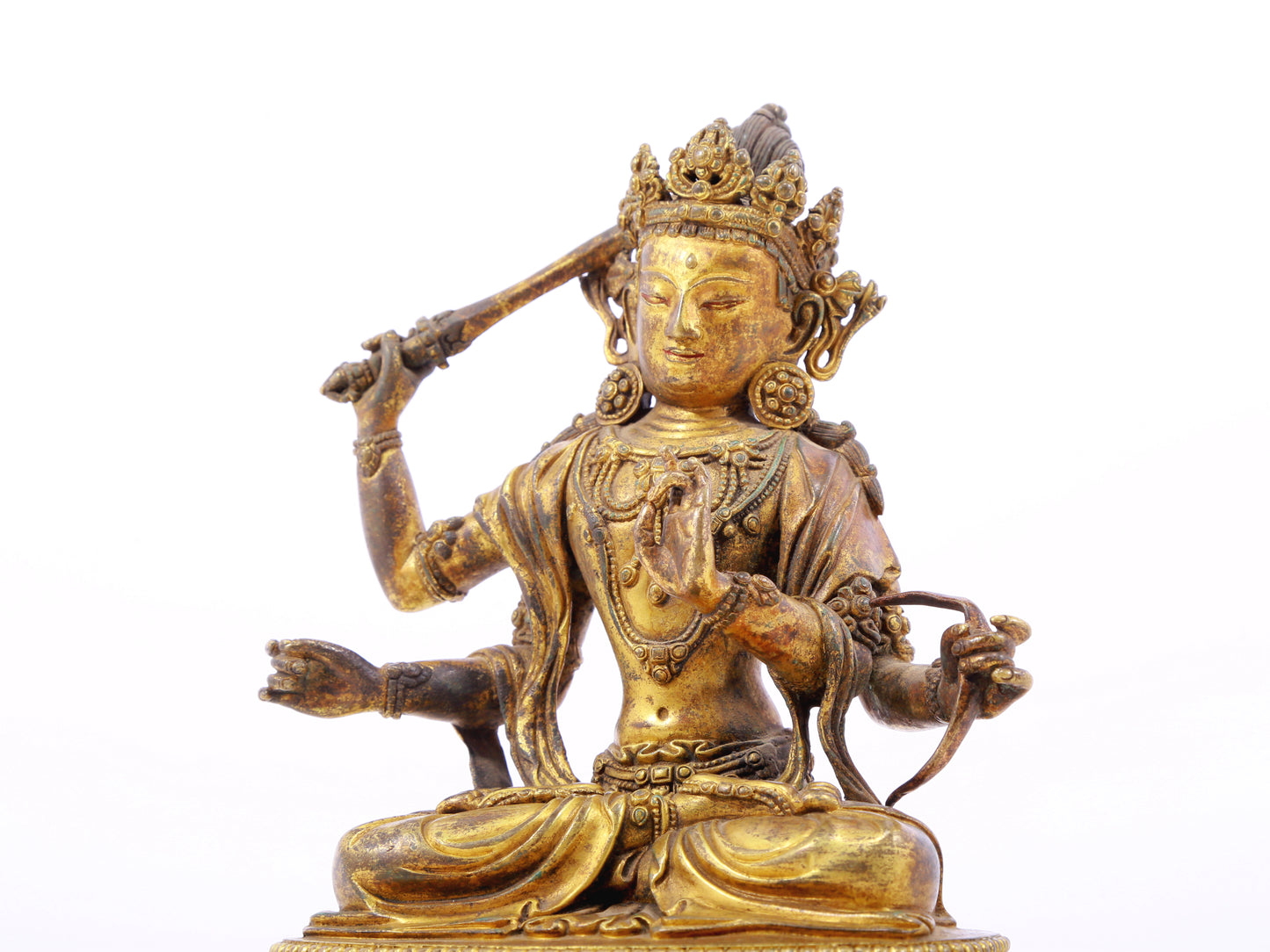 A serene gilt bronze statue of Manjusri with four arms