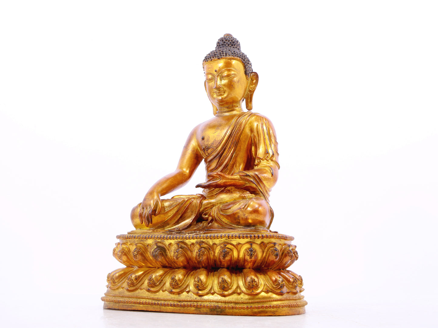 A solemn gilt bronze statue of Gautama Buddha