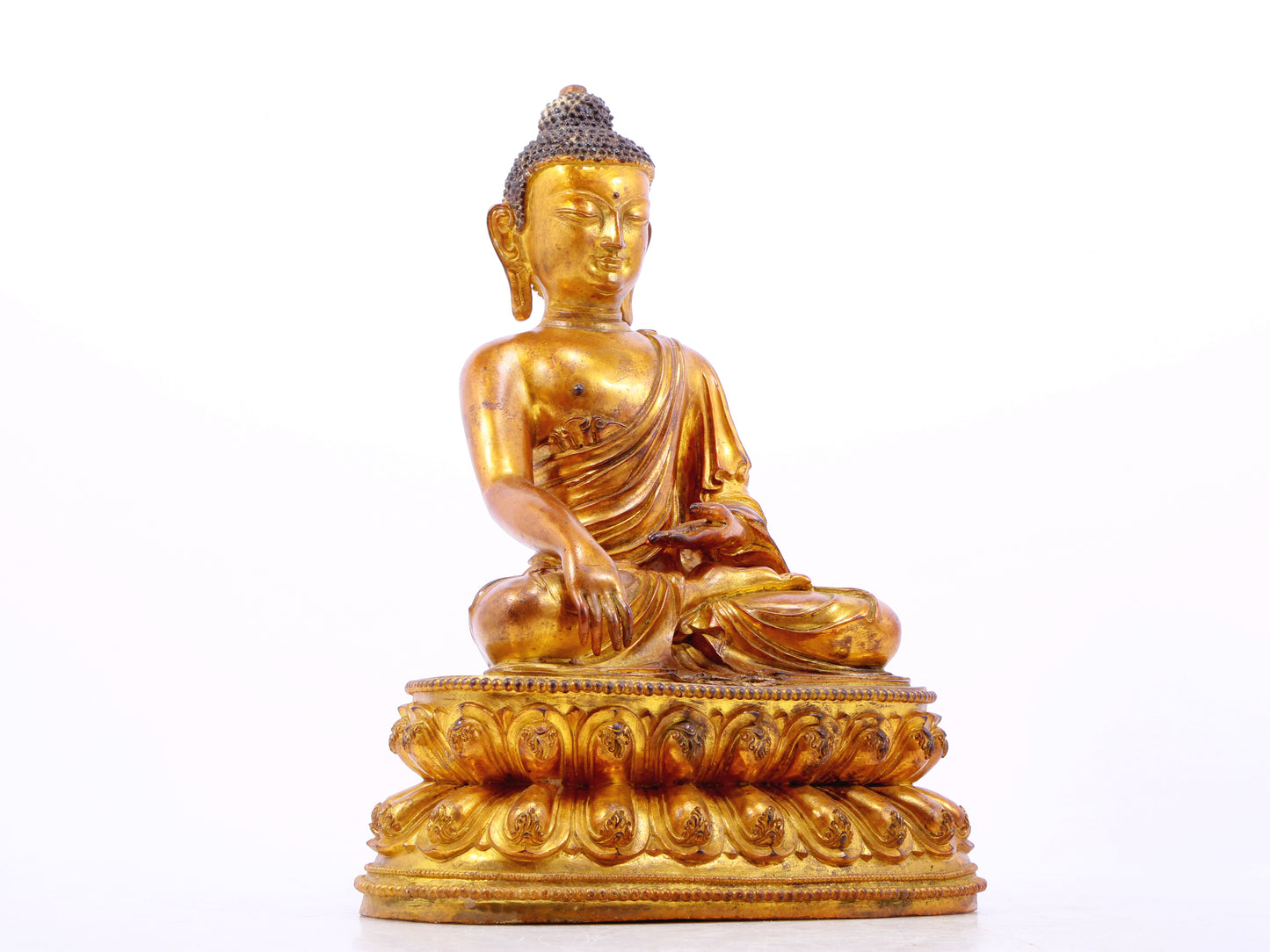 A solemn gilt bronze statue of Gautama Buddha