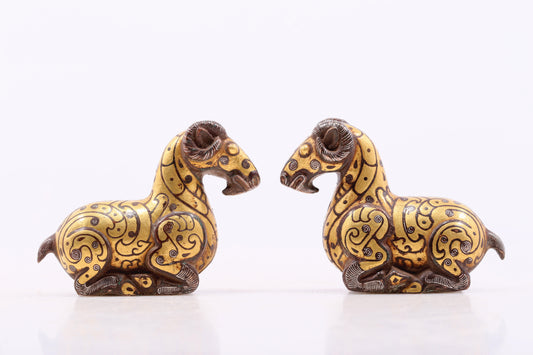 A pair of bronze inlaid gold and silver goat ornaments