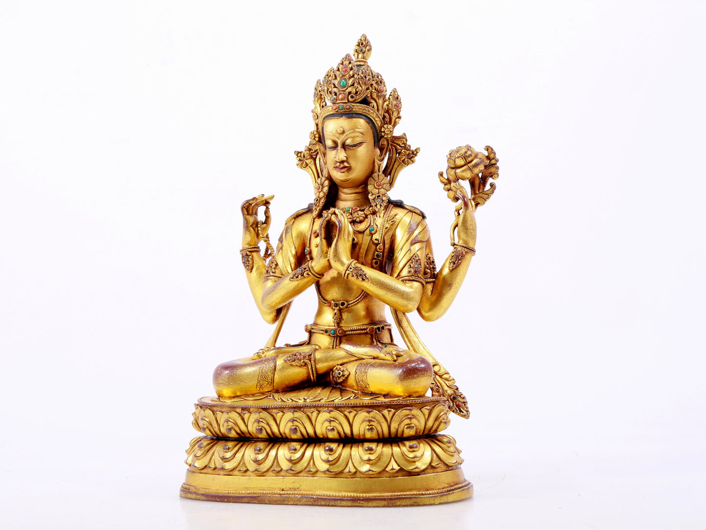 A solemn gilt bronze statue of Guanyin with four arms inlaid with hundreds of treasures