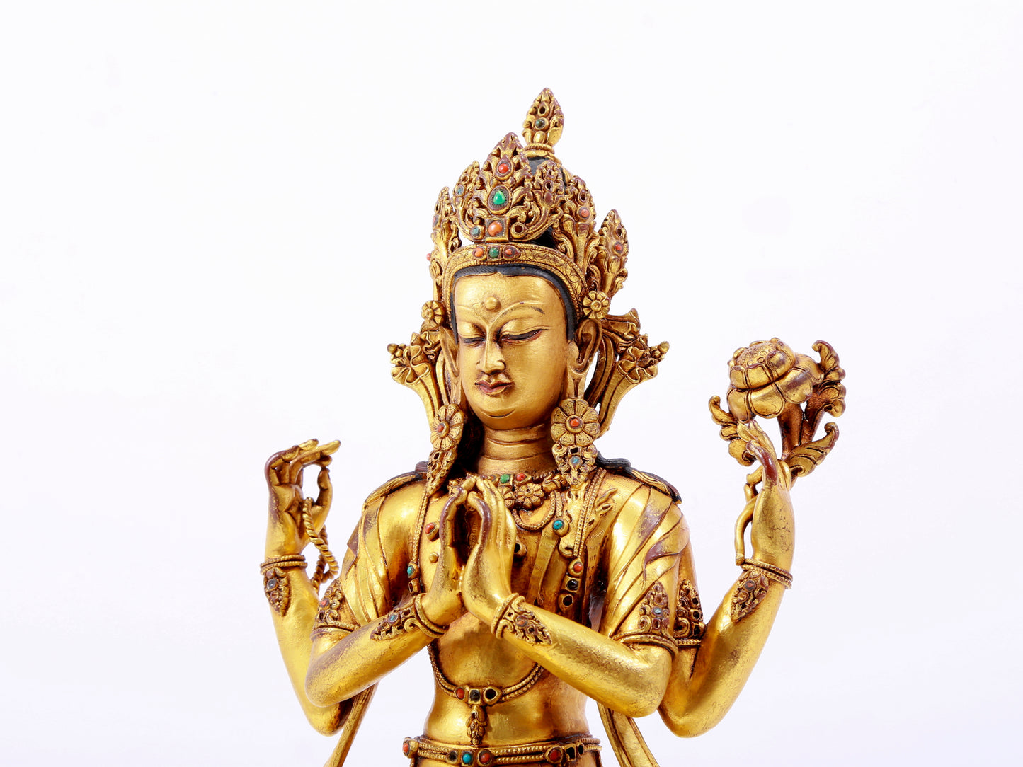 A solemn gilt bronze statue of Guanyin with four arms inlaid with hundreds of treasures