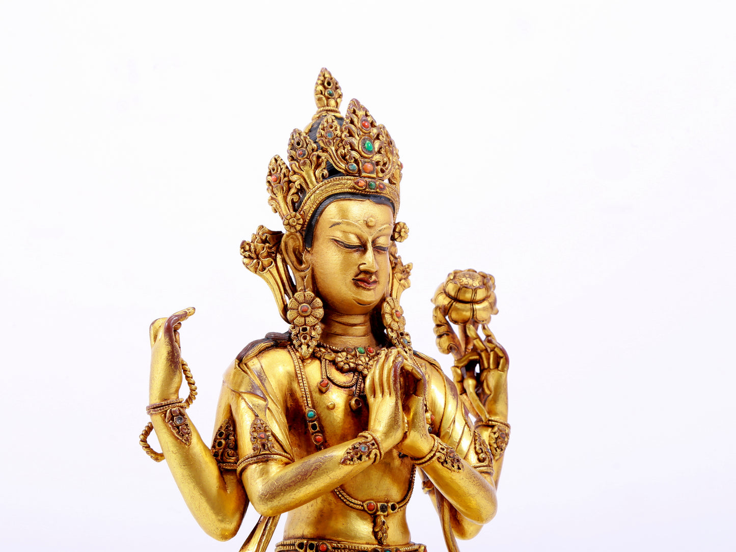 A solemn gilt bronze statue of Guanyin with four arms inlaid with hundreds of treasures